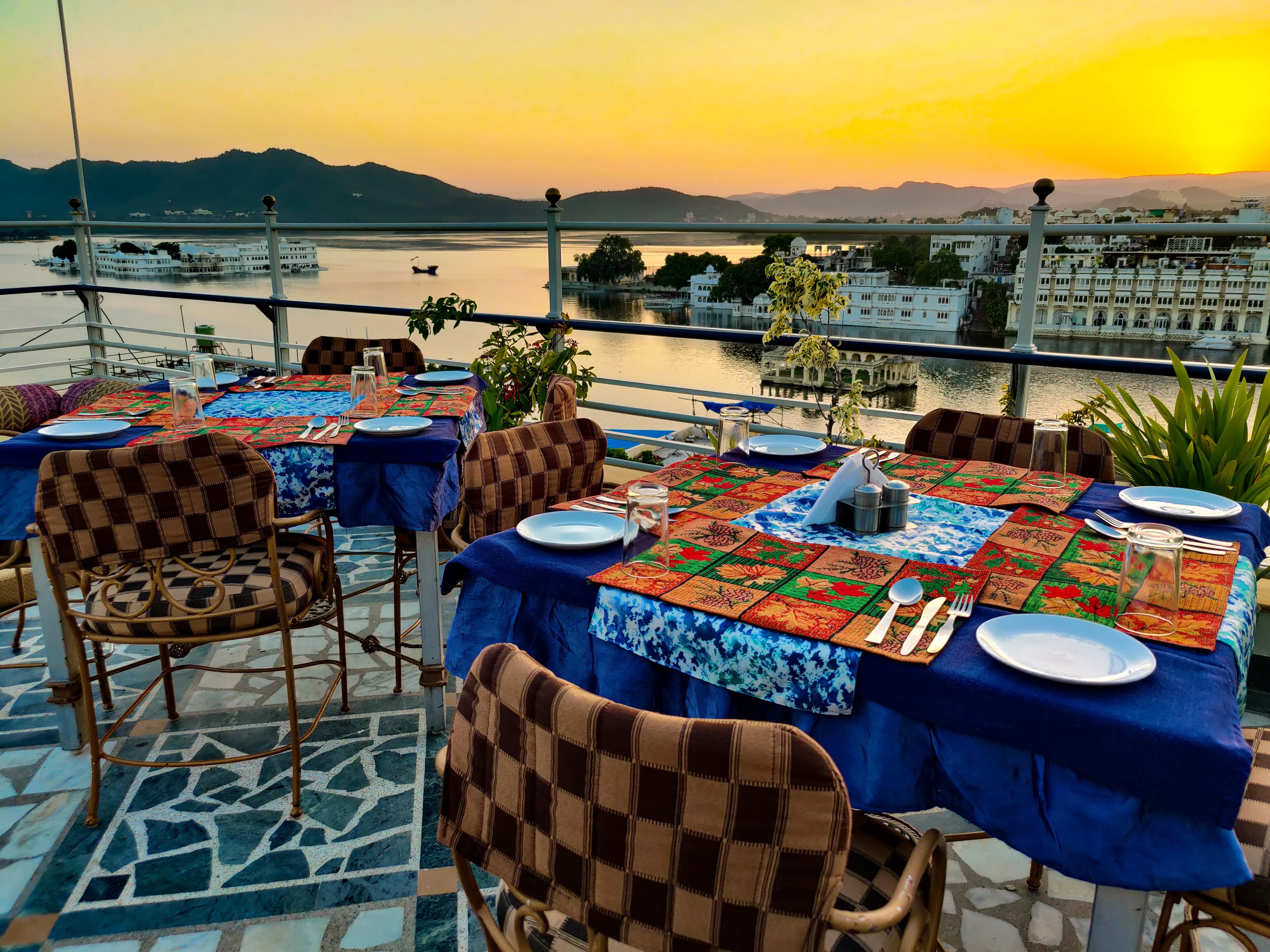 Mesa lista para comer con vista a un lago y edificios al fondo.