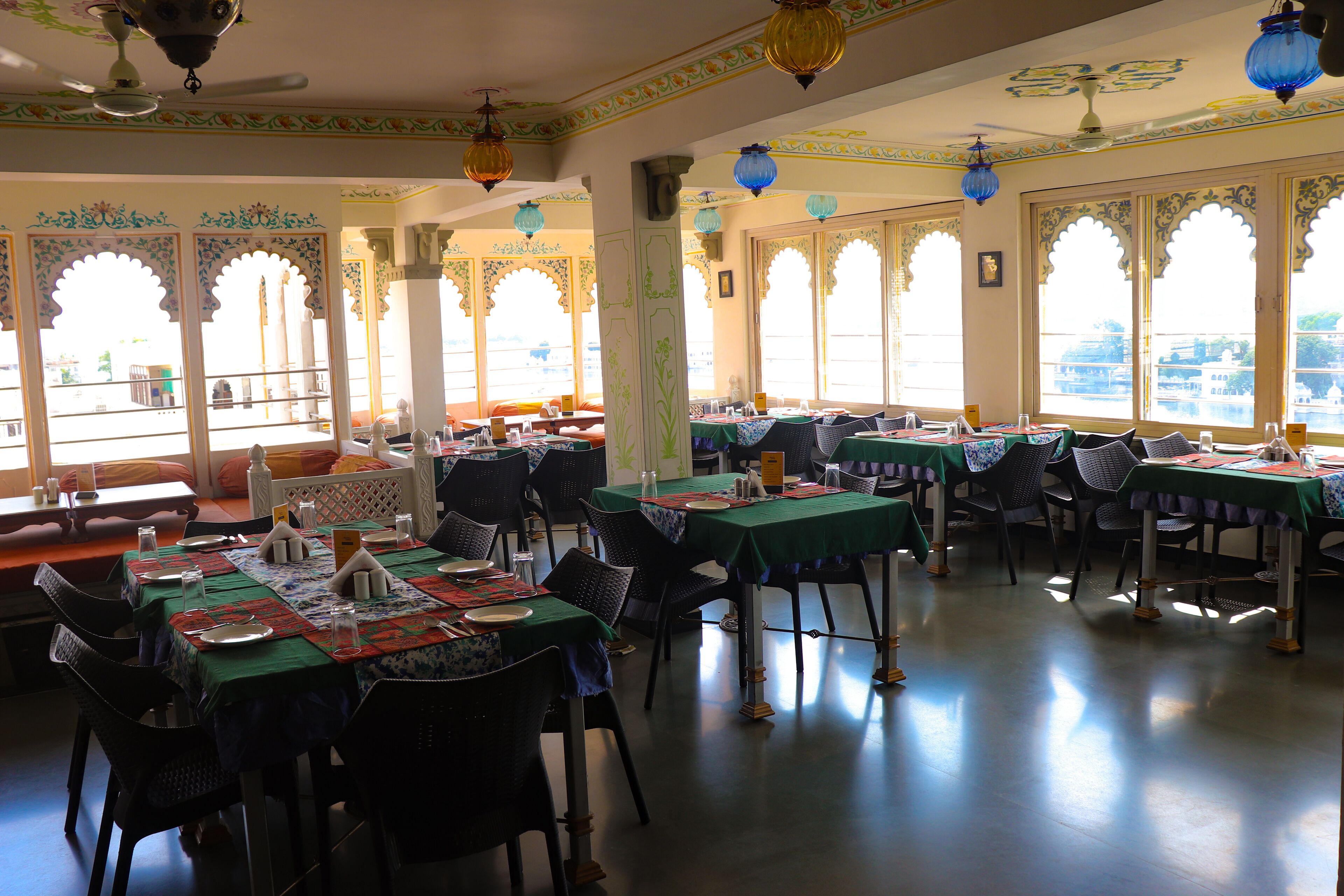 A restaurant with multiple tables, chairs, and decorative elements such as lanterns and patterned windows.