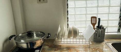 A kitchen with a stove, a dish rack, and a window with blinds.