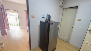 Eine kleine Küche mit einem schwarzen Kühlschrank, einem Wasserspender und einem Wasserkocher darauf.