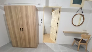 Ein Zimmer mit einem Holzschrank, einem Sessel, einem kleinen Tisch und einem Spiegel an der Wand.