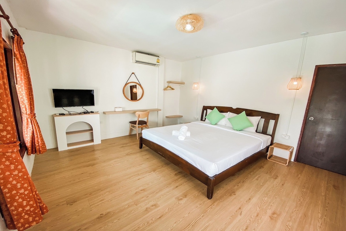 A bedroom with a wooden bed, a television, a desk, and a wardrobe.