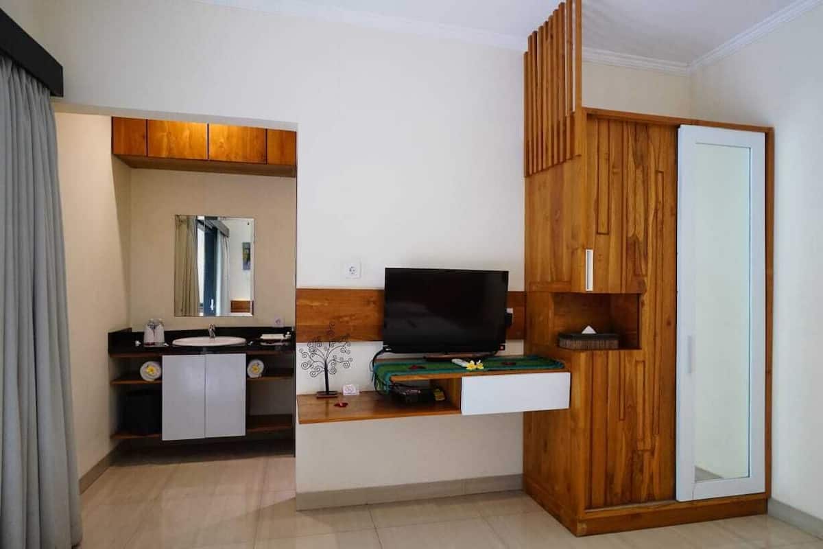 Un baño moderno con tocador, espejo y televisión montada en la pared.