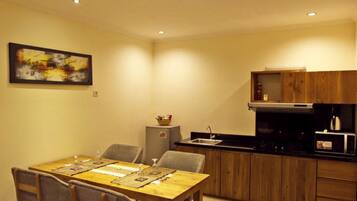 A compact kitchen with a dining table, chairs, a refrigerator, and a microwave.