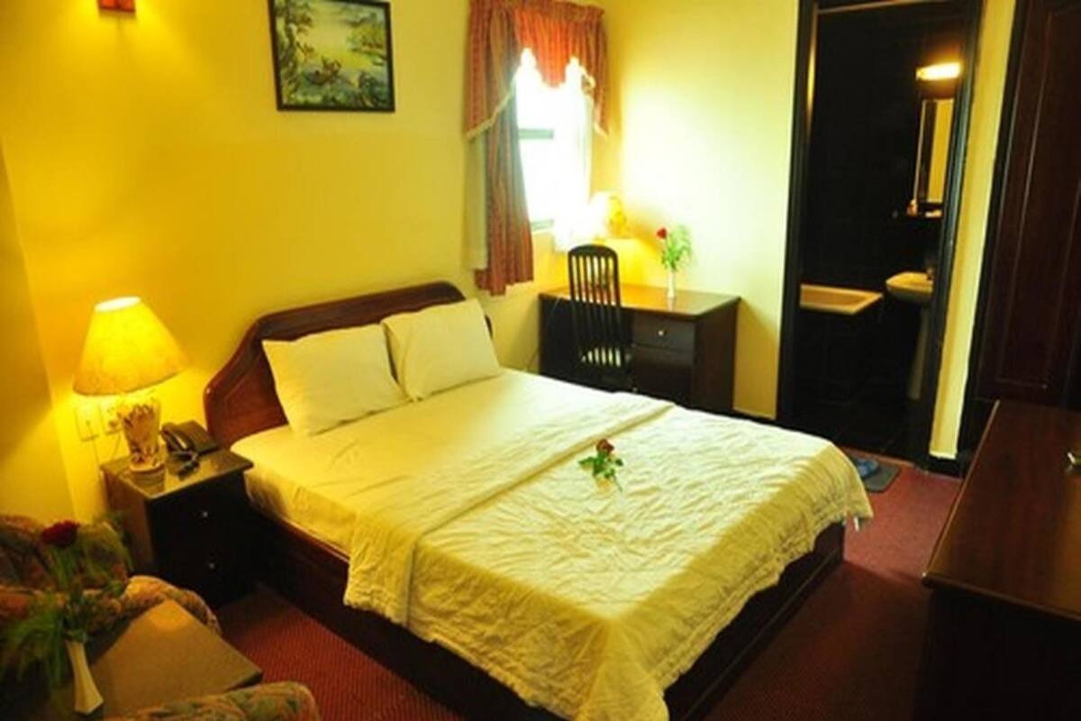 Ein Hotelzimmer mit Bett, Nachttisch, Stuhl, Schreibtisch und Badezimmer.