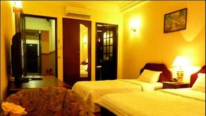 Una habitació d'hotel amb dos llits, una cadira, un escriptori i un mirall.
