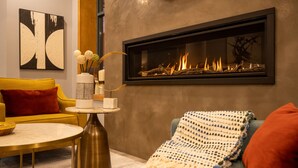 A modern living room with a fireplace, a yellow sofa, a round coffee table, and a blue armchair. - Alpenglow Lodge by MountainView (Whistler)