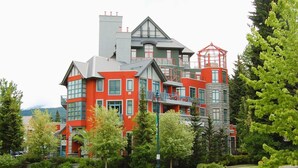 A multi-story building with a red facade, multiple balconies, and a prominent red tower. - Alpenglow Lodge by MountainView (Whistler)