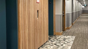 A hotel corridor with wooden paneling, numbered doors, and patterned carpet. - Alpenglow Lodge by MountainView (Whistler)