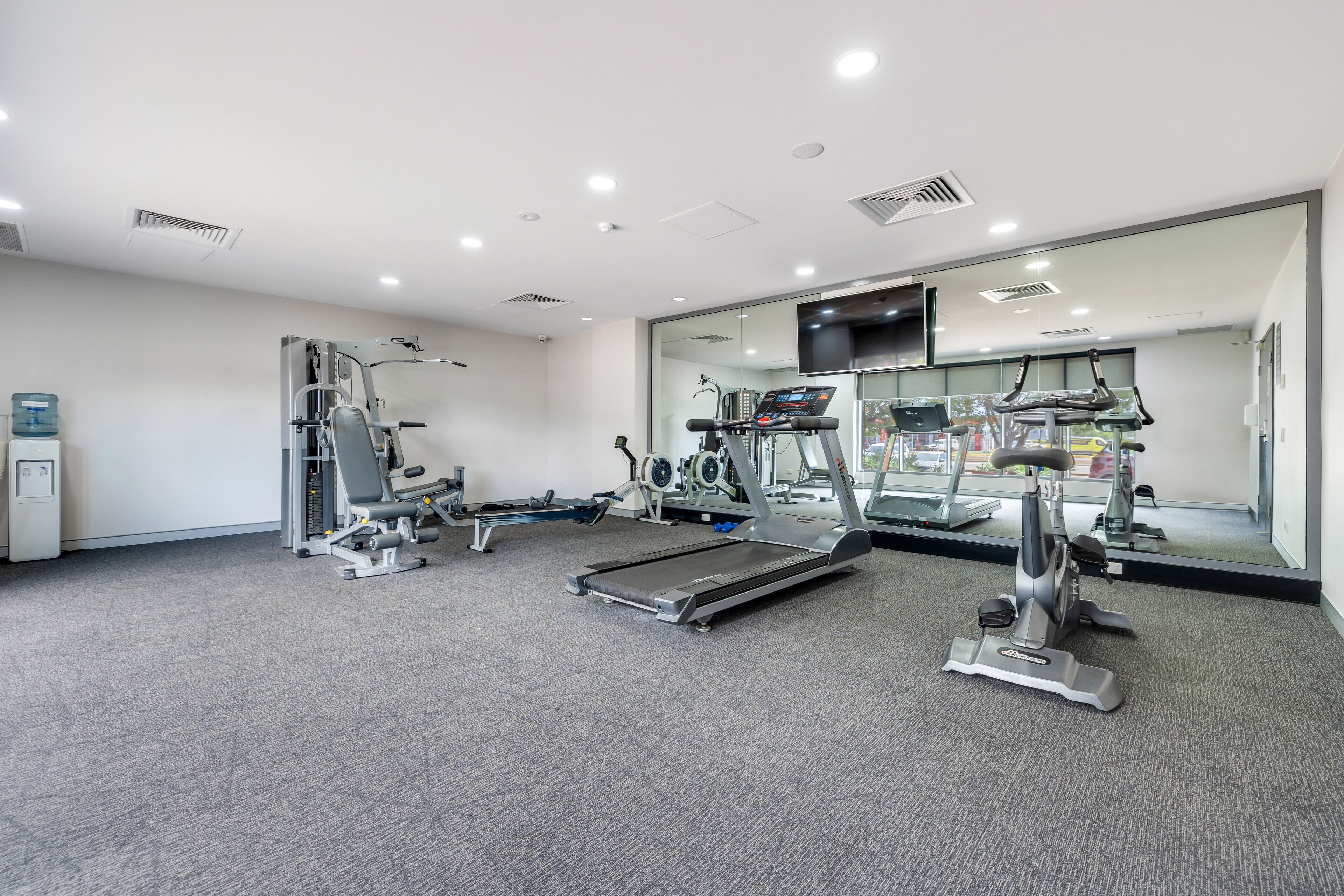 A gym with treadmills, elliptical machines, and weight equipment.