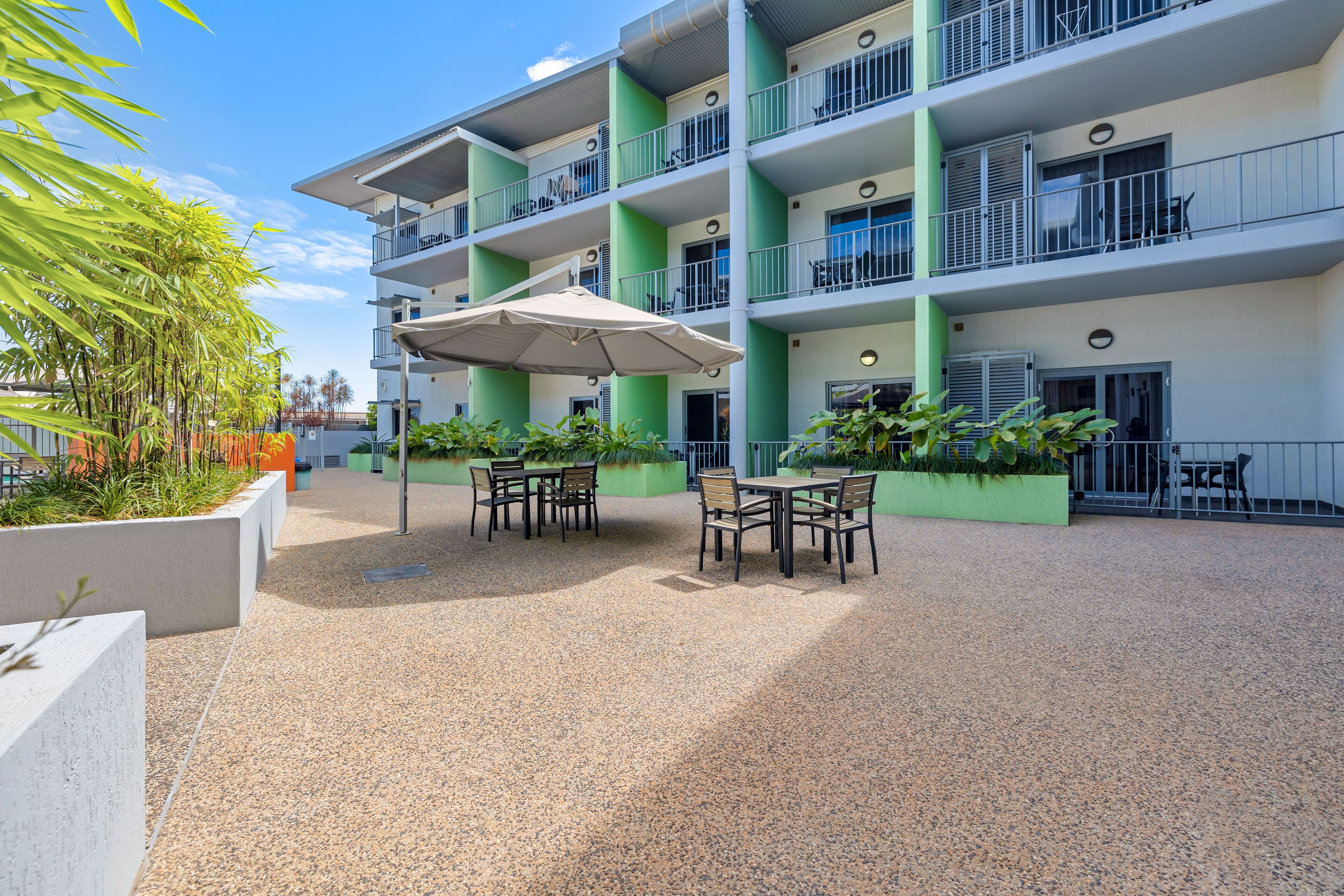A multi-story hotel with outdoor seating and greenery.