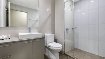 A modern bathroom with a toilet, sink, and glass-enclosed shower.