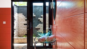 A bathroom with a glass-topped sink, a towel rack, and a view of a stone wall and greenery outside.