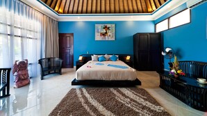 A modern bedroom with a large bed, a wooden ceiling, and a blue wall.