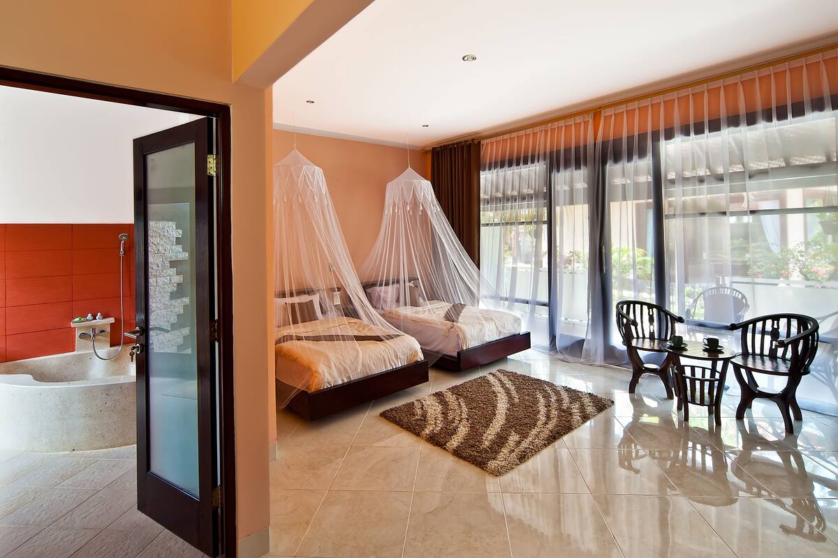 A hotel room with a bed, a sitting area with chairs, a small table, and a view of the outdoors.