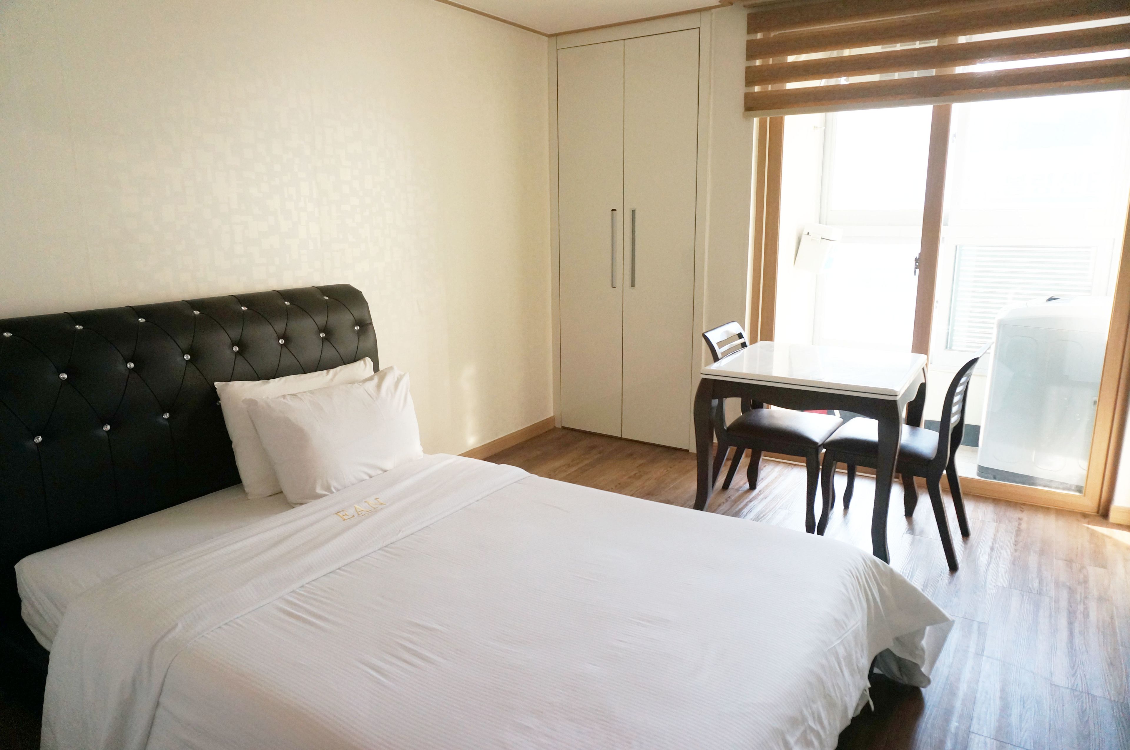 A bedroom with a bed, a desk, and a chair.
