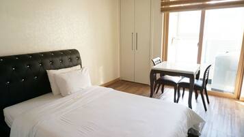 A bedroom with a bed, a desk, and a chair.