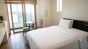 A bedroom with a bed, a small table, a chair, and a wardrobe. - EAN Residence Hotel (Daejeon)