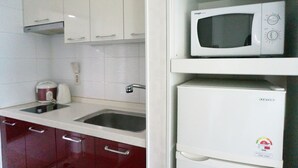 A kitchen with white cabinets, a microwave, a kettle, and a sink. - EAN Residence Hotel (Daejeon)