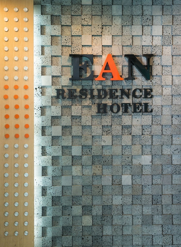 Un letrero de hotel con el nombre 'BAN RESIDENCE HOTEL' en letras grandes, sobre un muro de azulejos con motas.