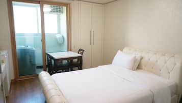 Een slaapkamer met een bed, een tafel en een stoel. Er is een schuifdeur die leidt naar een balkon.