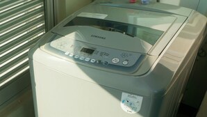 A Samsung washing machine with a control panel, a water inlet, and a drain hose. - EAN Residence Hotel (Daejeon)