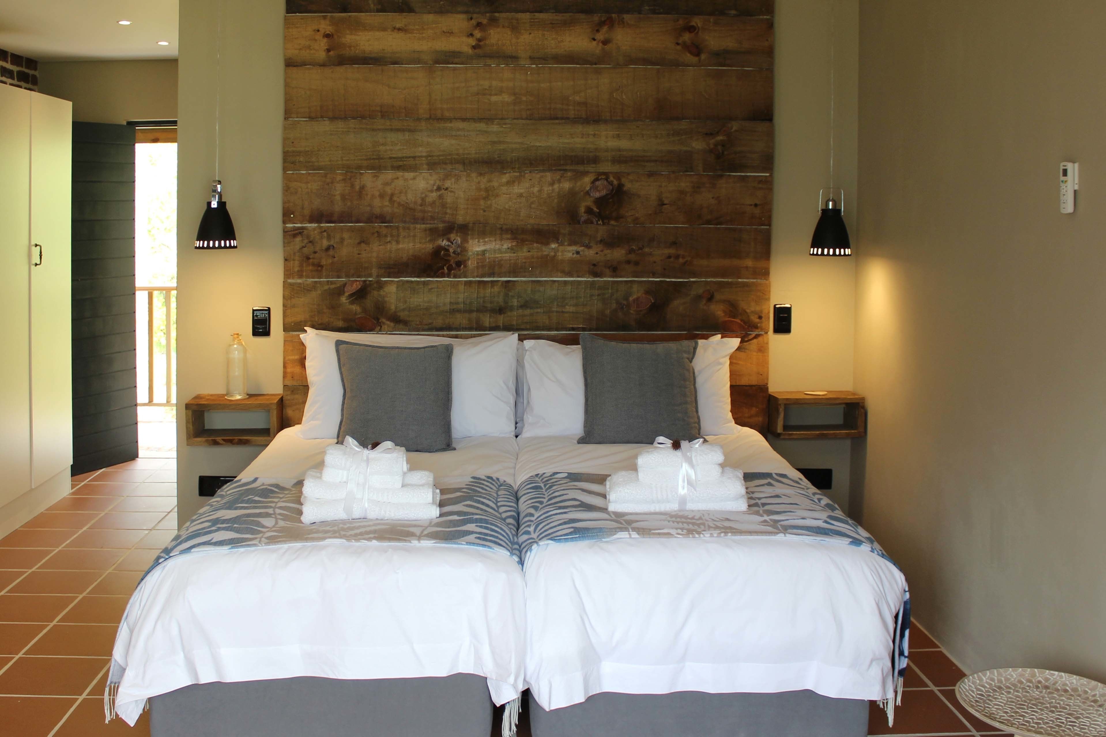 A double bed with a wooden headboard, two bedside tables with lamps, and a bathroom visible in the background.
