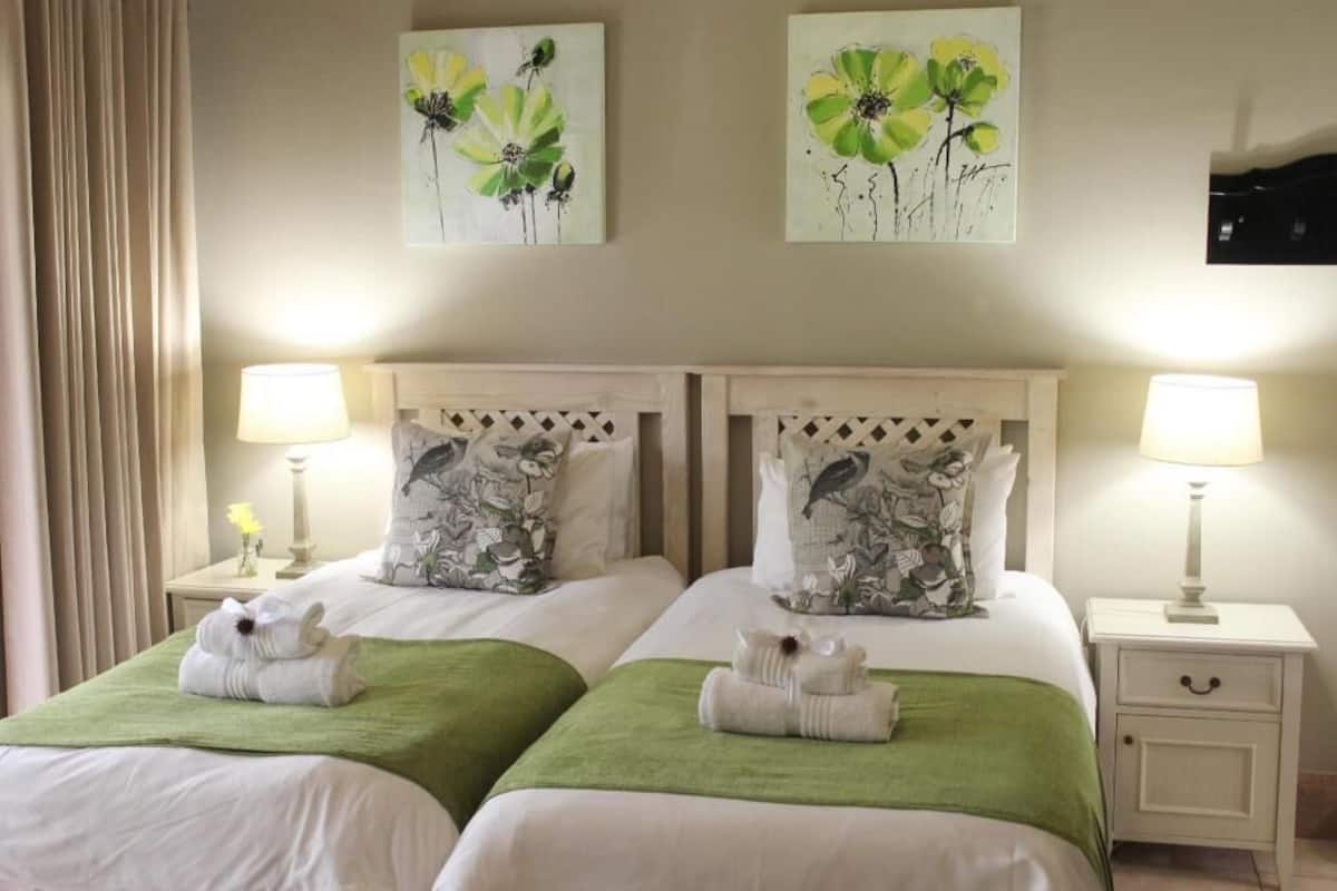 A double room with two beds, each with a pillow and a lamp.