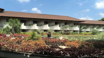 A building with a tiled roof and multiple balconies, surrounded by a variety of potted plants and shrubs.