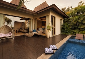 Un moderno resort con piscina, mobiliario exterior y exuberante vegetación.