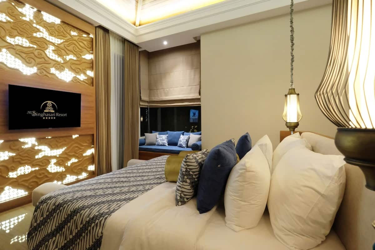 Ein Hotelzimmer mit einem Bett, einem an der Wand montierten Fernseher und einer dekorativen Wandverkleidung.