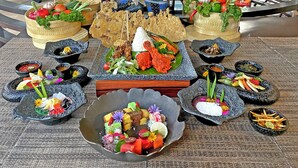 A table with various dishes and a decorative figure. - The Singhasari Resort (Batu)