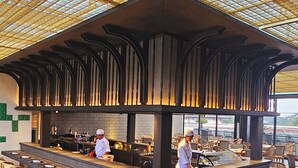 A restaurant with a high ceiling, a central bar area, and outdoor seating. - The Singhasari Resort (Batu)