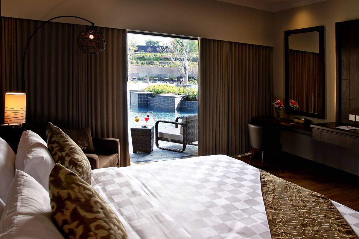 Ein Hotelzimmer mit Bett, Schreibtisch, Stuhl und Blick auf einen Außenpool.