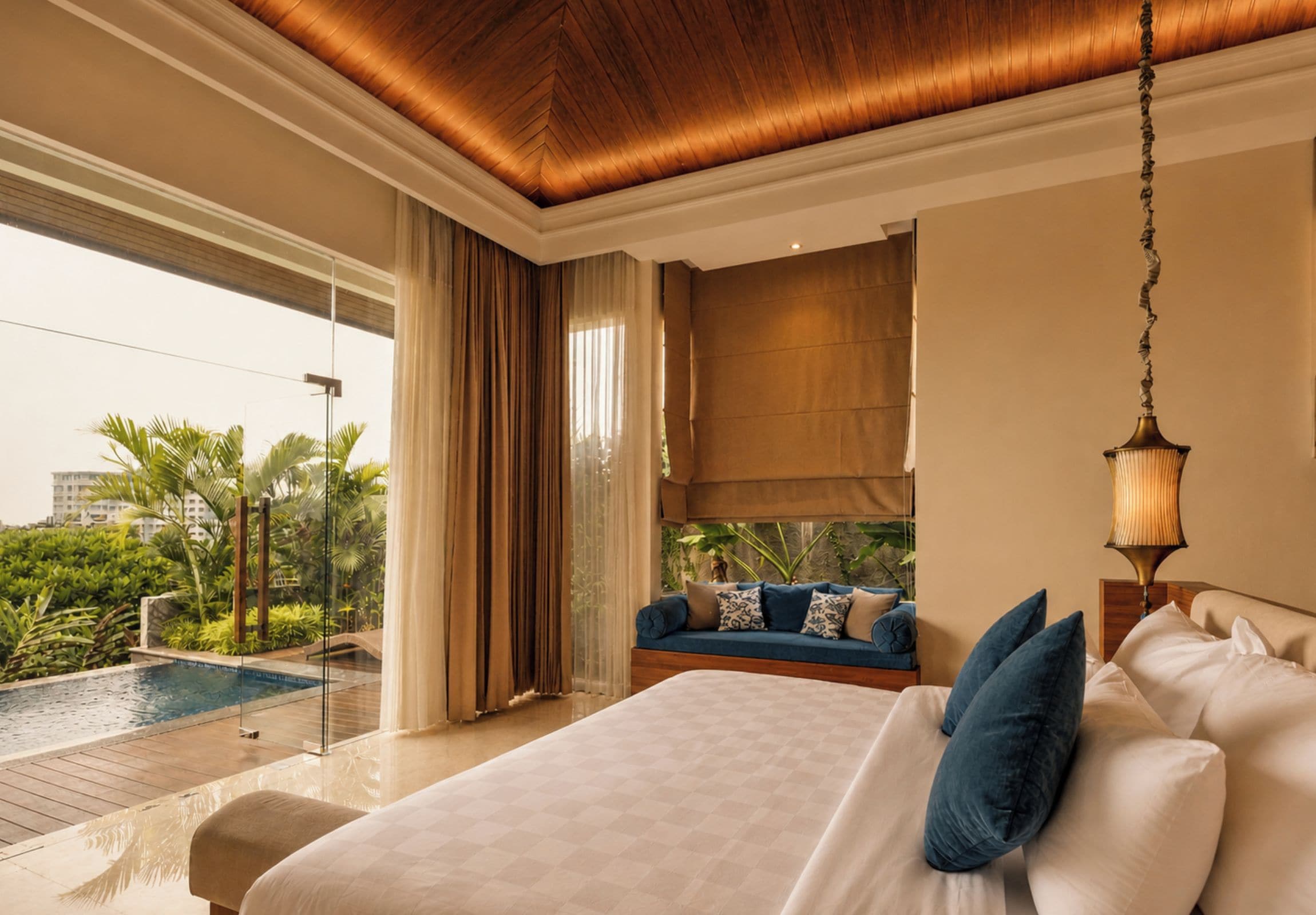 A spacious bedroom with a large bed, a sofa, and a view of a swimming pool and greenery.