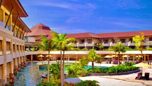 A hotel with a central pool, multiple balconies, and lush landscaping. - The Singhasari Resort (Batu)