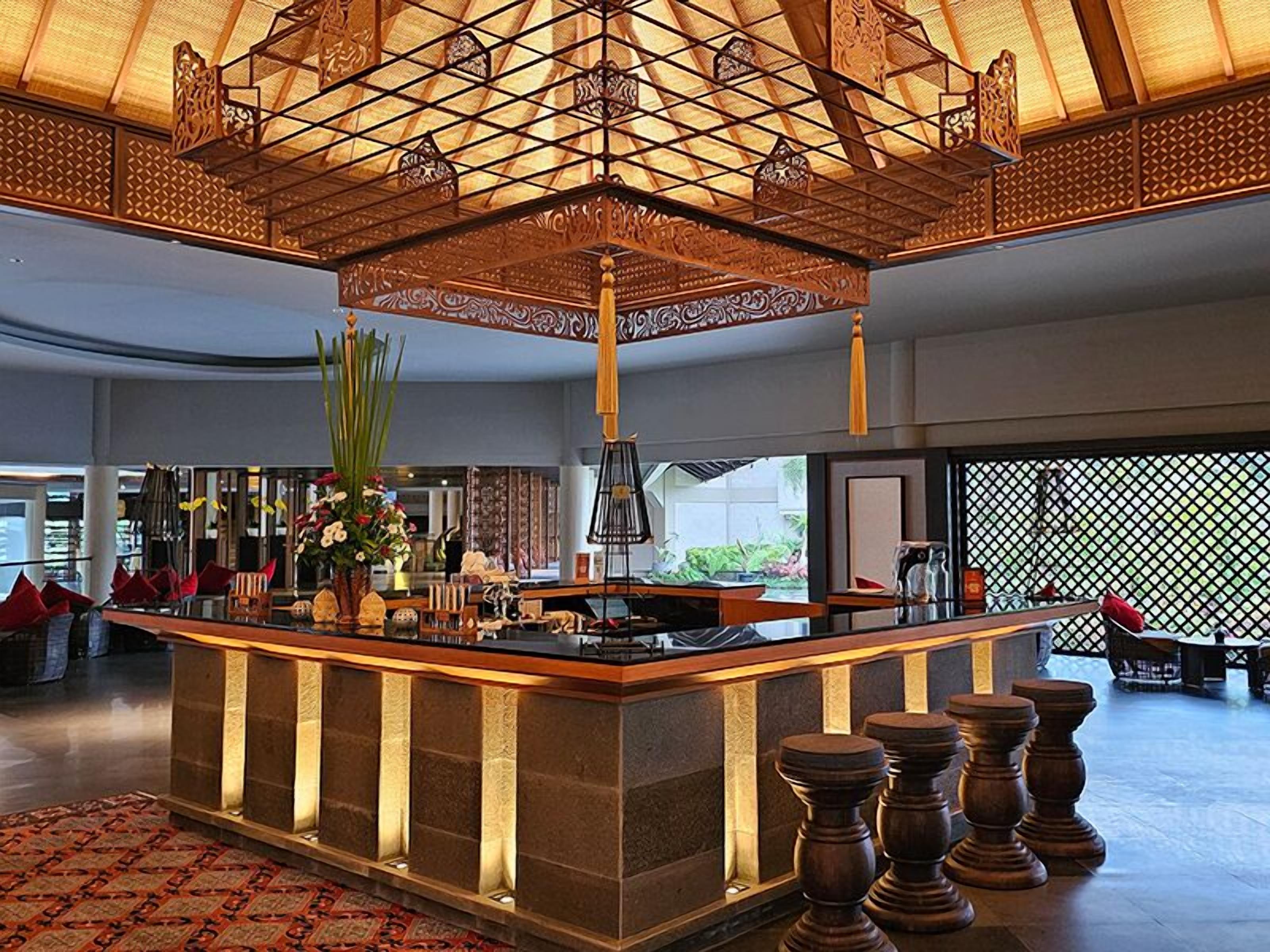 A spacious lobby with a central bar area, a decorative ceiling, and a view of the outdoors.