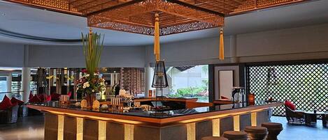 A spacious lobby with a central bar area, a decorative ceiling, and a view of the outdoors.