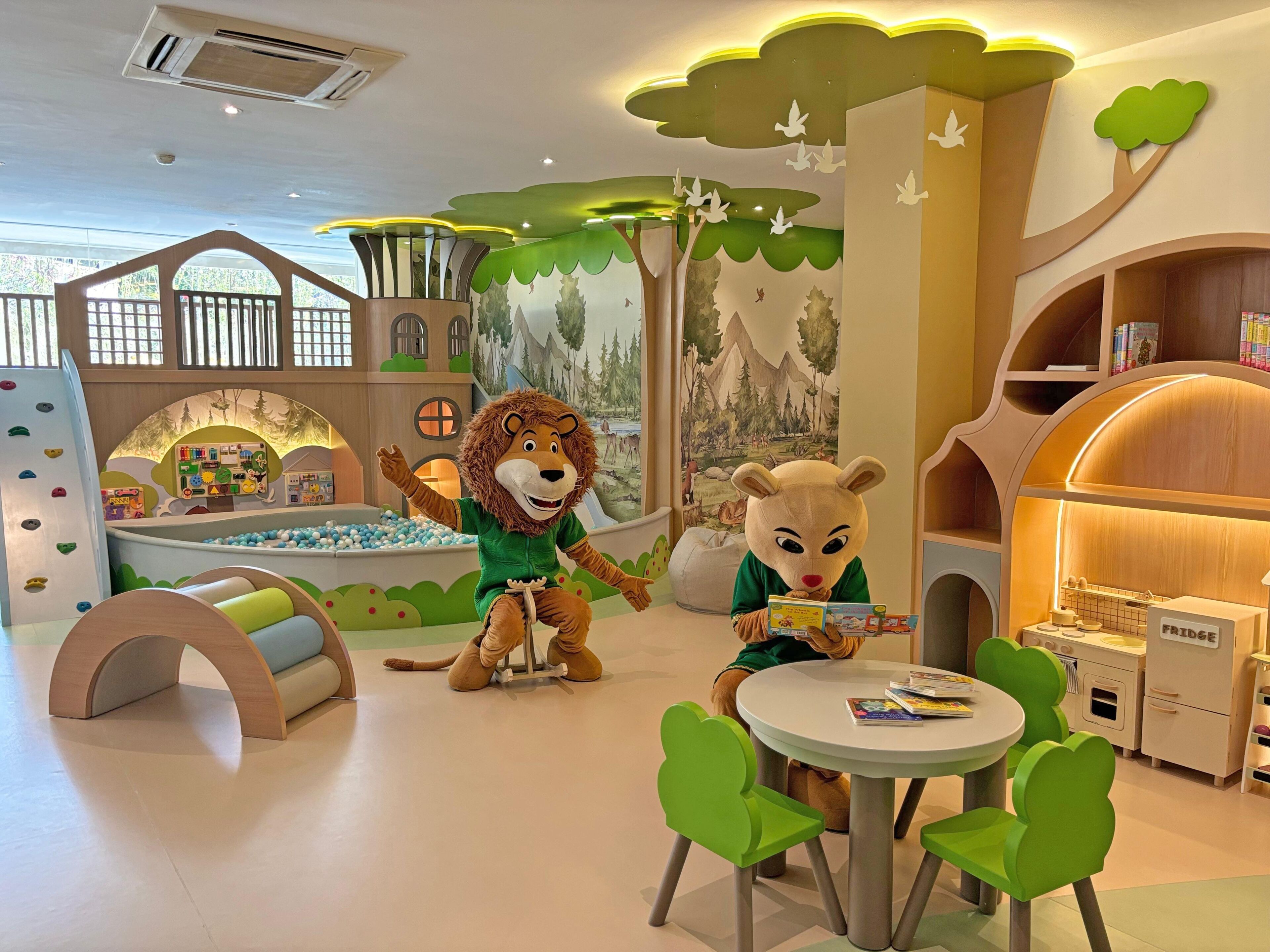 A children's play area with a lion mascot, a ball pit, and a reading nook with a bear mascot.
