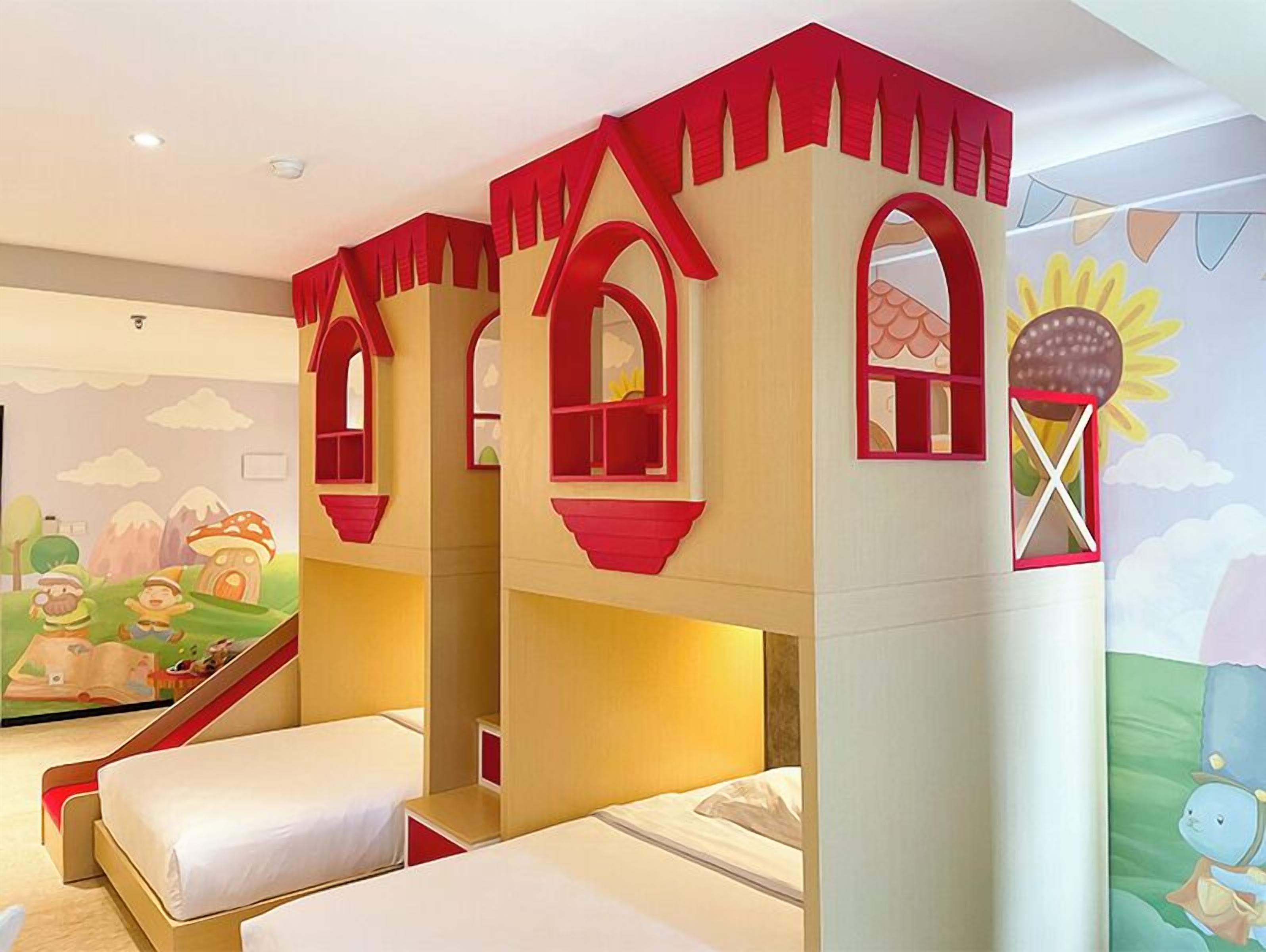 Zona de juegos infantiles con temática de castillo, que incluye un tobogán y un mural con un sol y nubes.