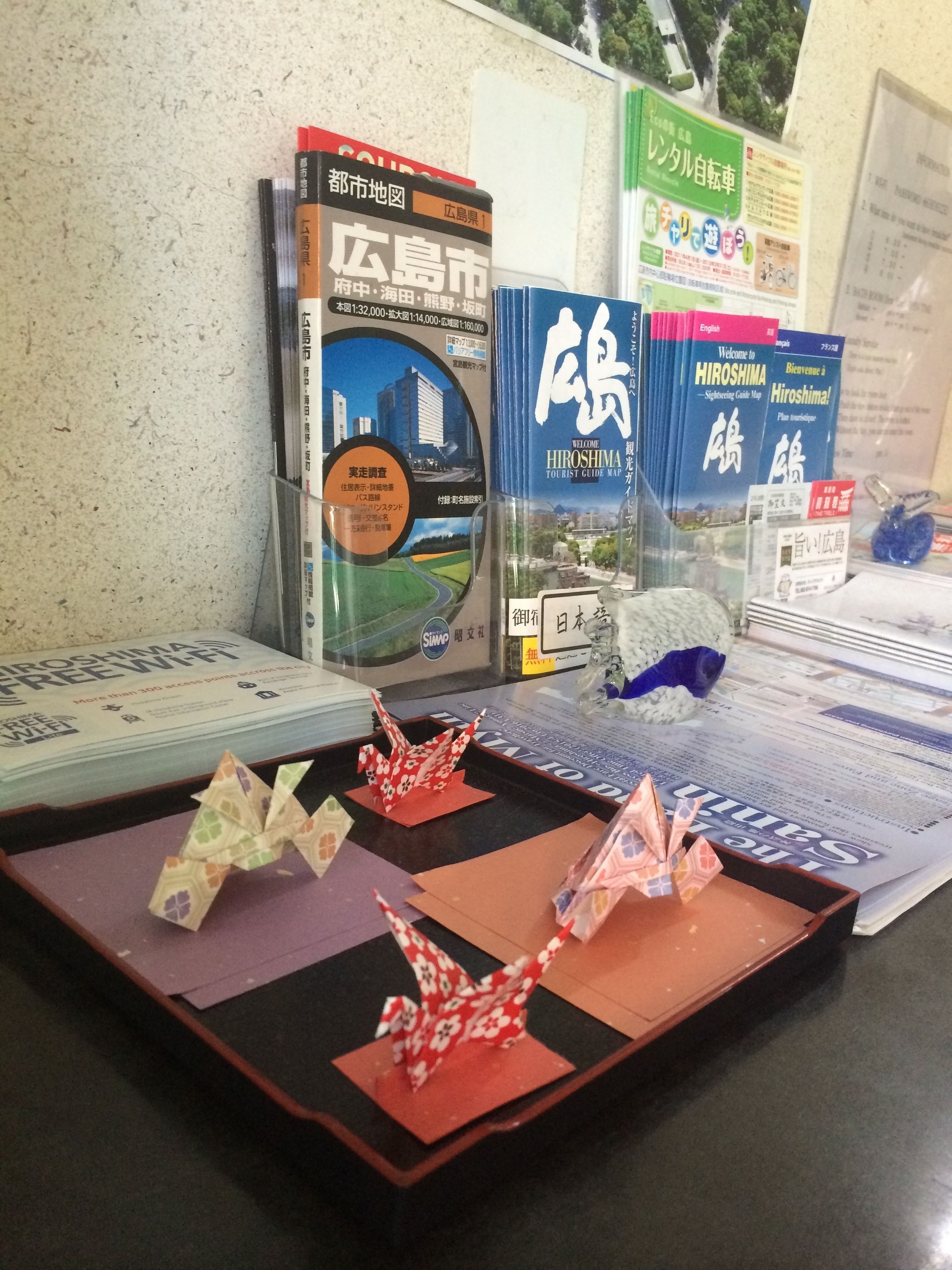 A desk with travel brochures, a map, and origami figures.