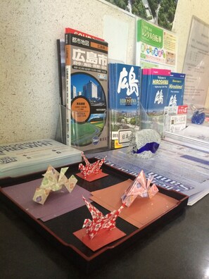 A desk with travel brochures, a map, and origami figures. - Kasuga Ryokan (Hiroshima)