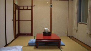 Una habitación japonesa tradicional con suelo de tatami, una mesa baja de madera con un hervidor de agua y una puerta corredera.