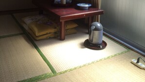 Una habitación tradicional japonesa con suelo de tatami, una mesa de madera baja con utensilios de cocina, una tetera y un fusuma con vistas.