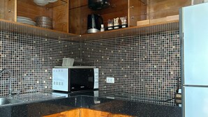 Cocina con armarios de madera, microondas y cafetera.