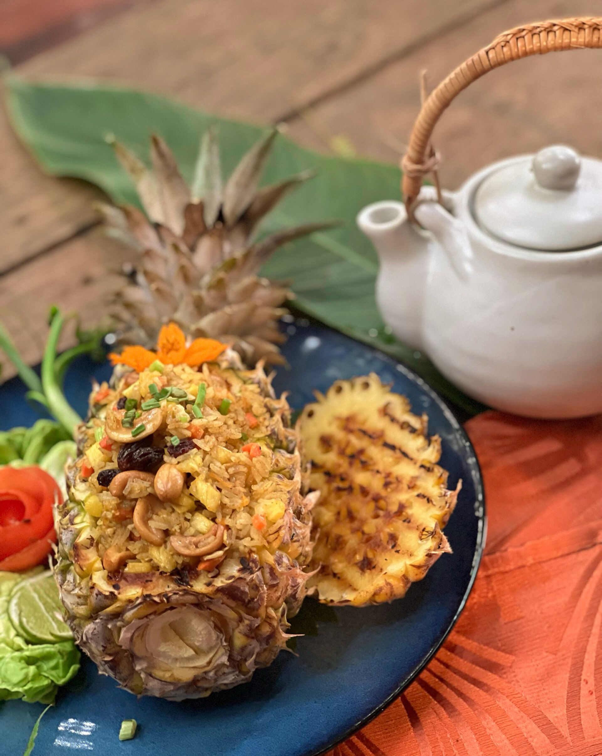 Un piatto con ananas ripiena, una fetta di ananas e una teiera su un tavolo.