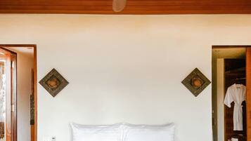 A bedroom with a bed, a ceiling fan, and two decorative wall pieces.