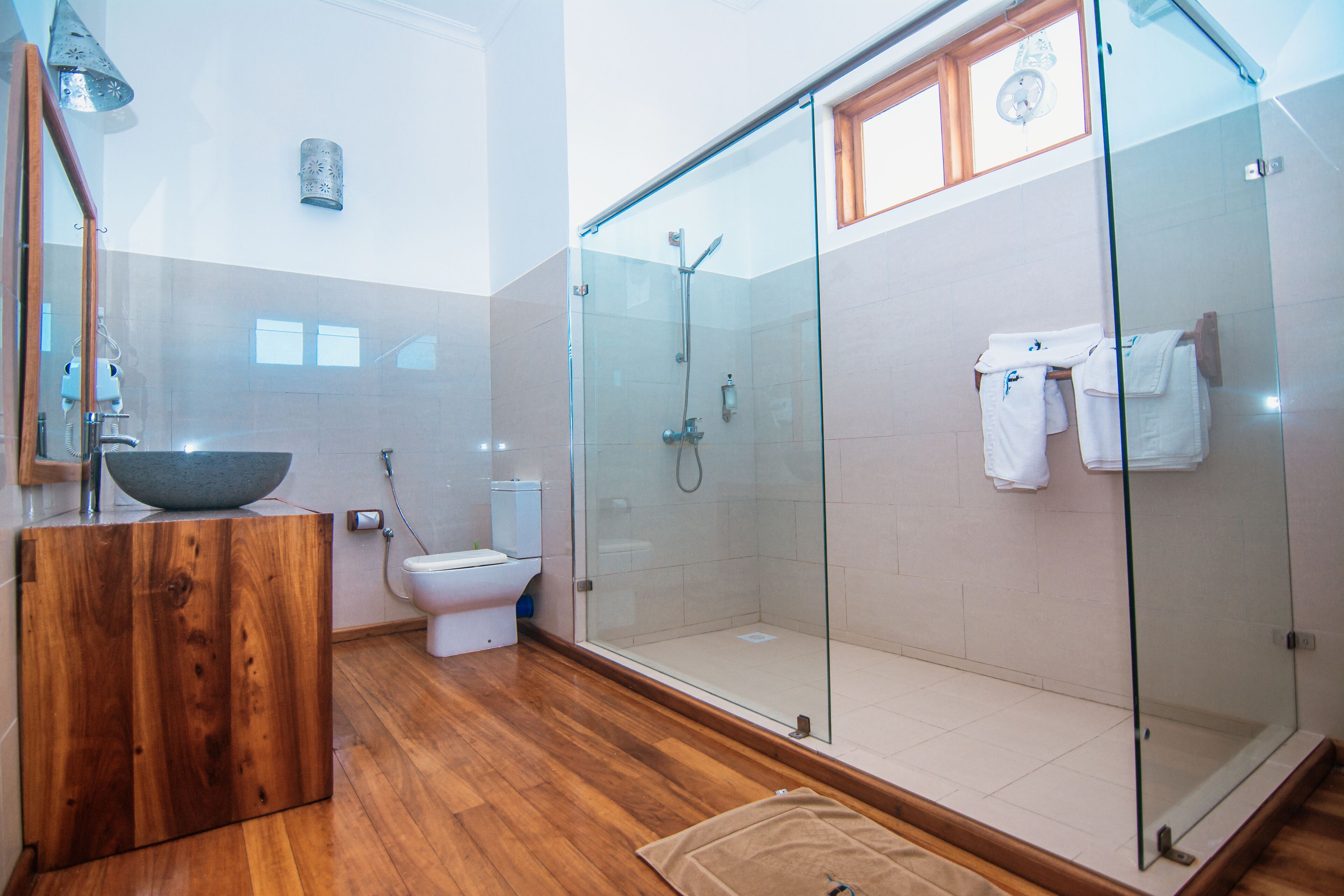 Un baño moderno con tocador de madera, cabina de ducha de vidrio y inodoro.