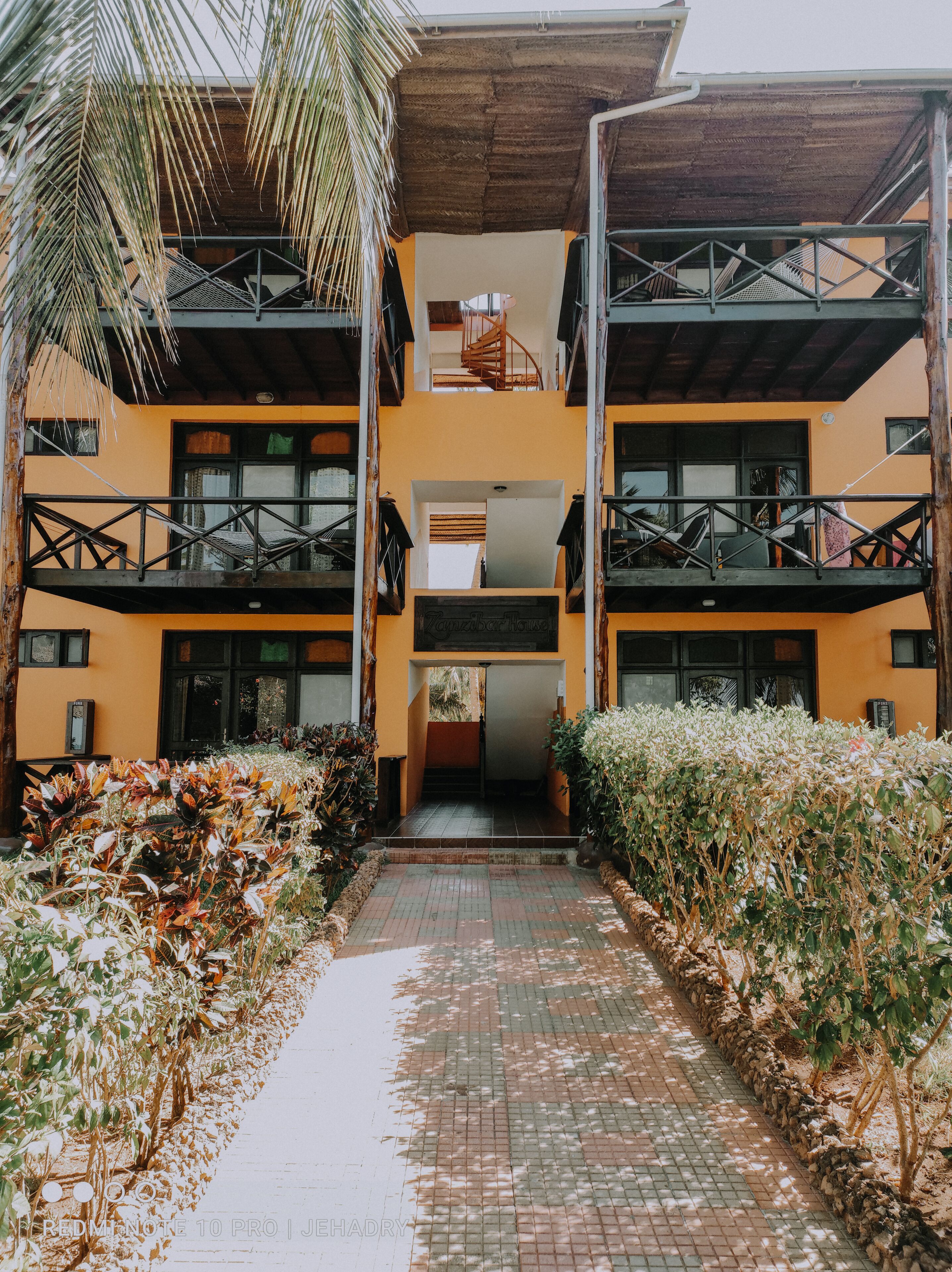 A two-story building with balconies, a central staircase, and a paved walkway.