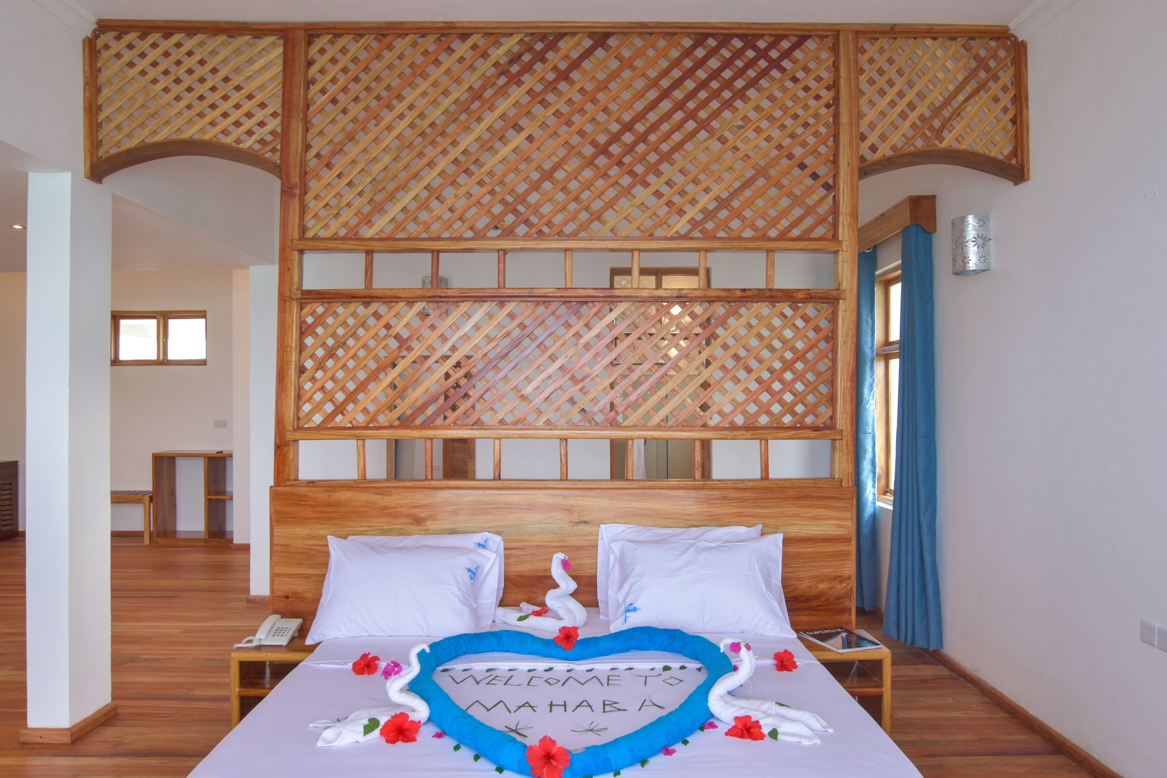 A hotel room with a bed, a wooden headboard, and a decorative wall panel.